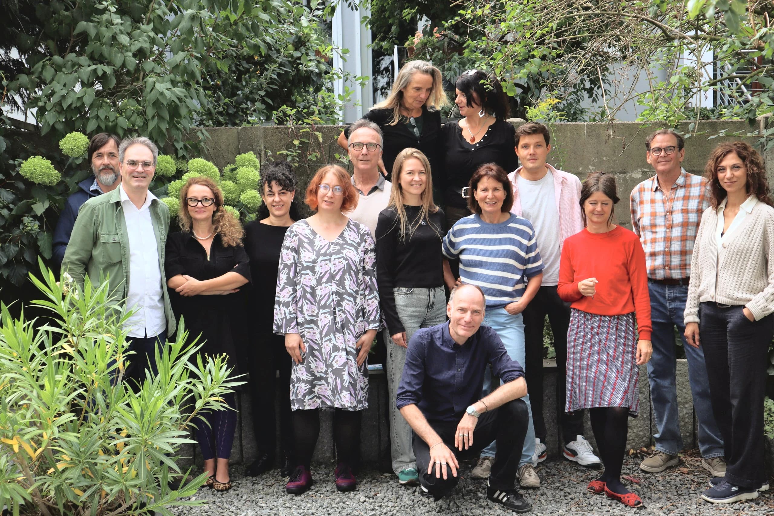 Das CASA-Team steht gemeinsam im begrünten Innenhof der Schule und lächelt in die Kamera