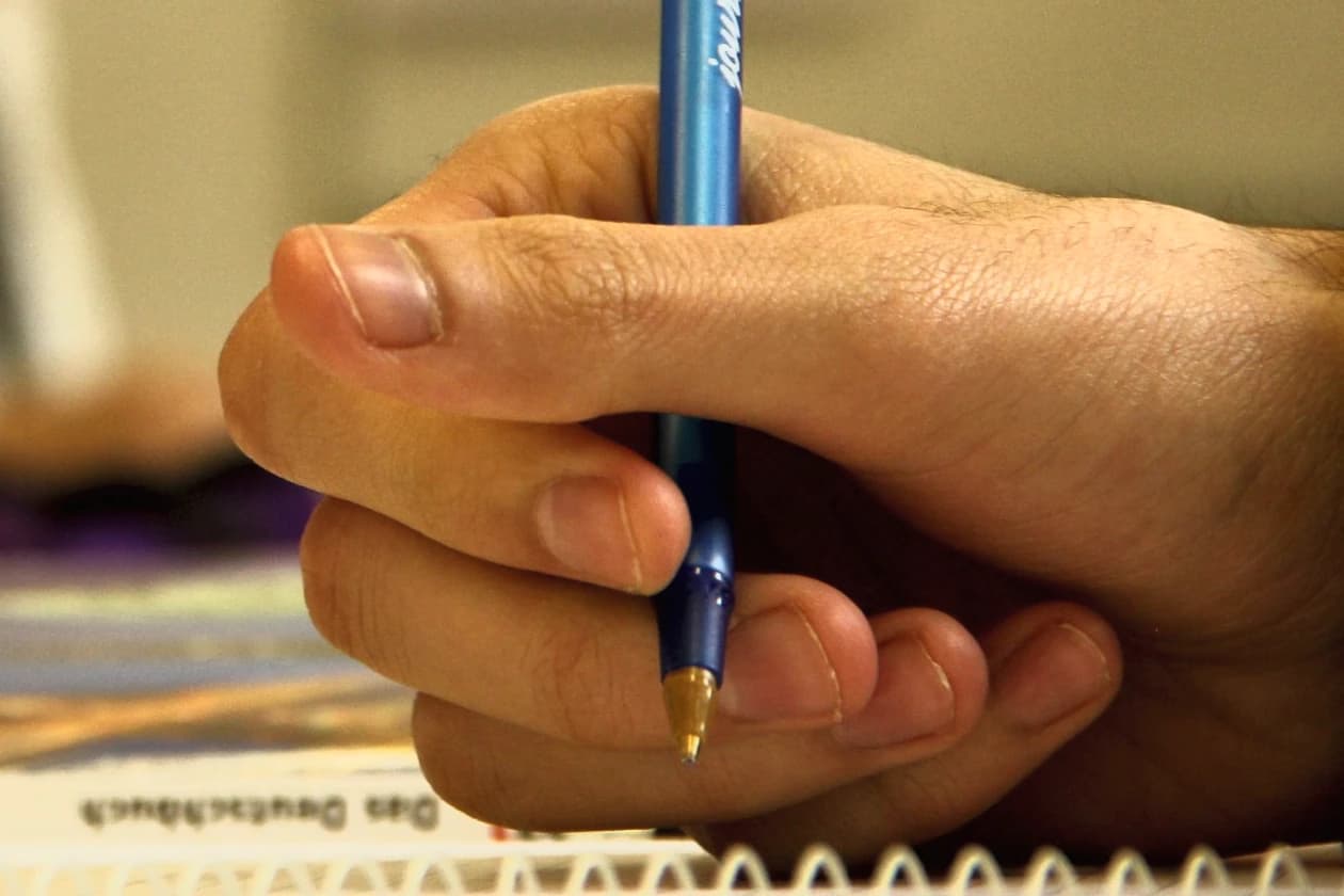 Eine Hand schreibt mit einem Stift auf Papier