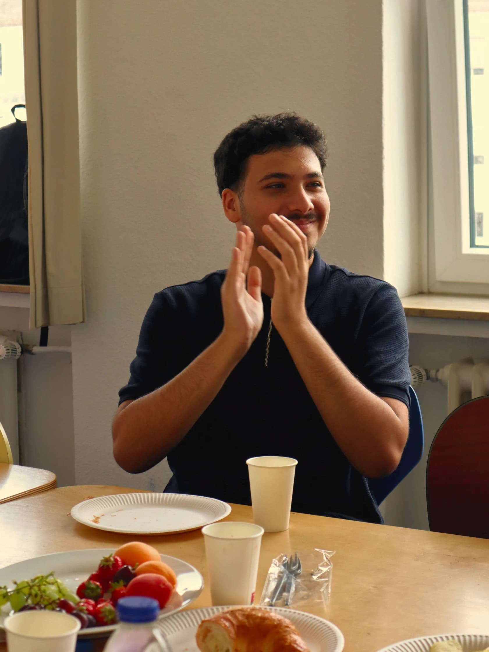 Ein Teilnehmer klatscht lachend beim gemeinsamen Frühstück