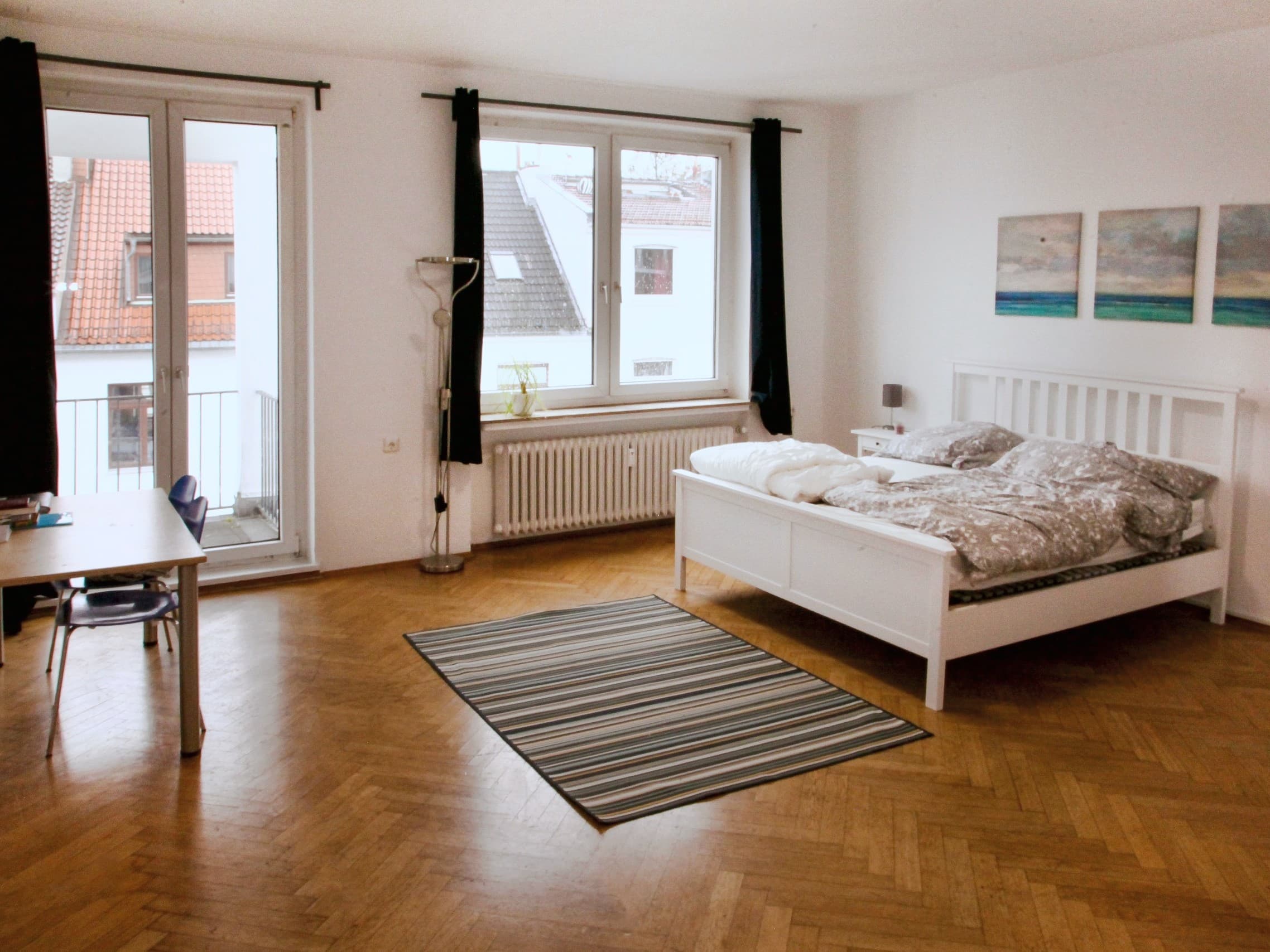 Beispielbild: Ein helles Zimmer in einer CASA-WG mit Bett, Schreibtisch und Balkontür