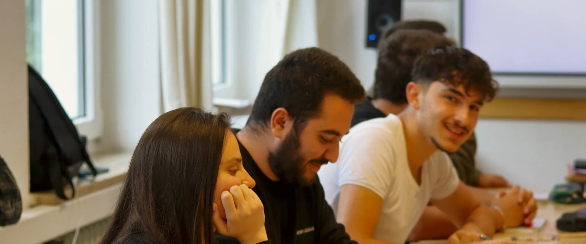 Drei Teilnehmende lachen bei einer gemeinsamen Übung